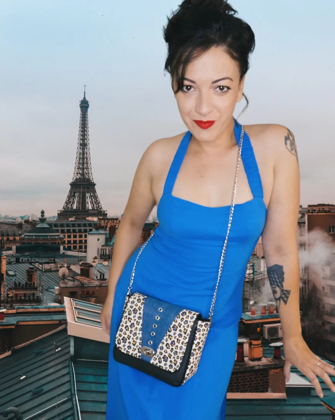 Sac à rabat motif léopard et empiècement jean recyclé décoré d'œillets en métal argent. Muni d'un fermoir tourniquet argent et d'une chaîne argent bandouilère amovible.