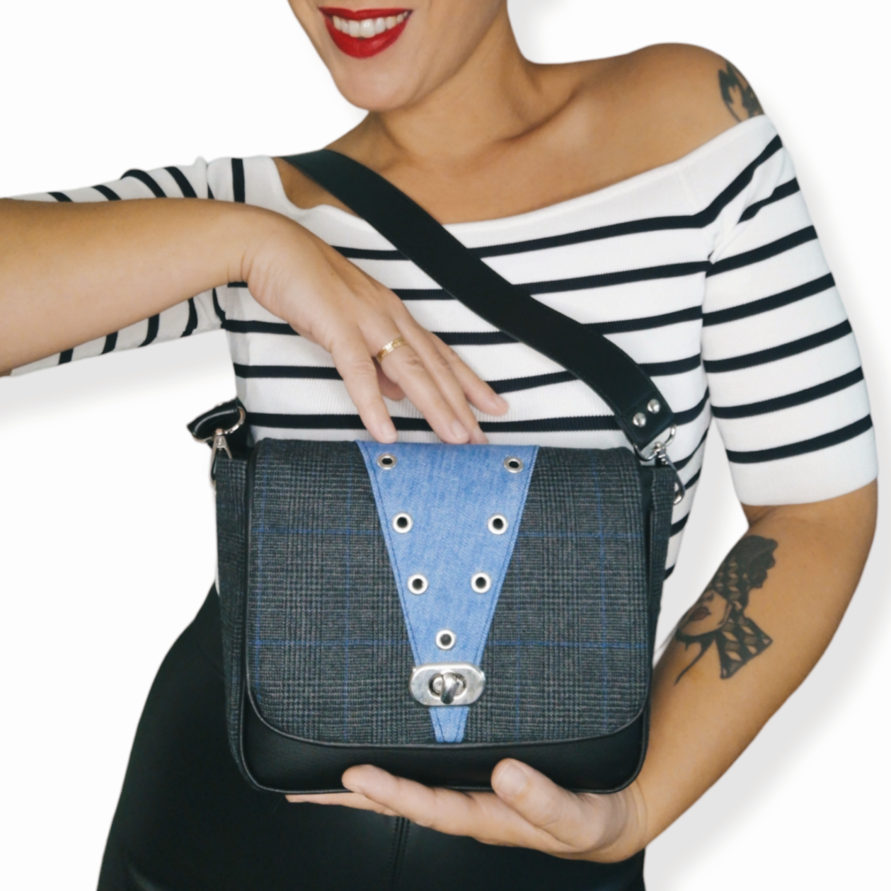 Sac à rabat motif tartan gris anthracite, noir et Bleu et empiècement jean recyclé décoré d'œillets en métal argent. Muni d'un fermoir tourniquet argent et d'une anse en simili cuir noir amovible.
