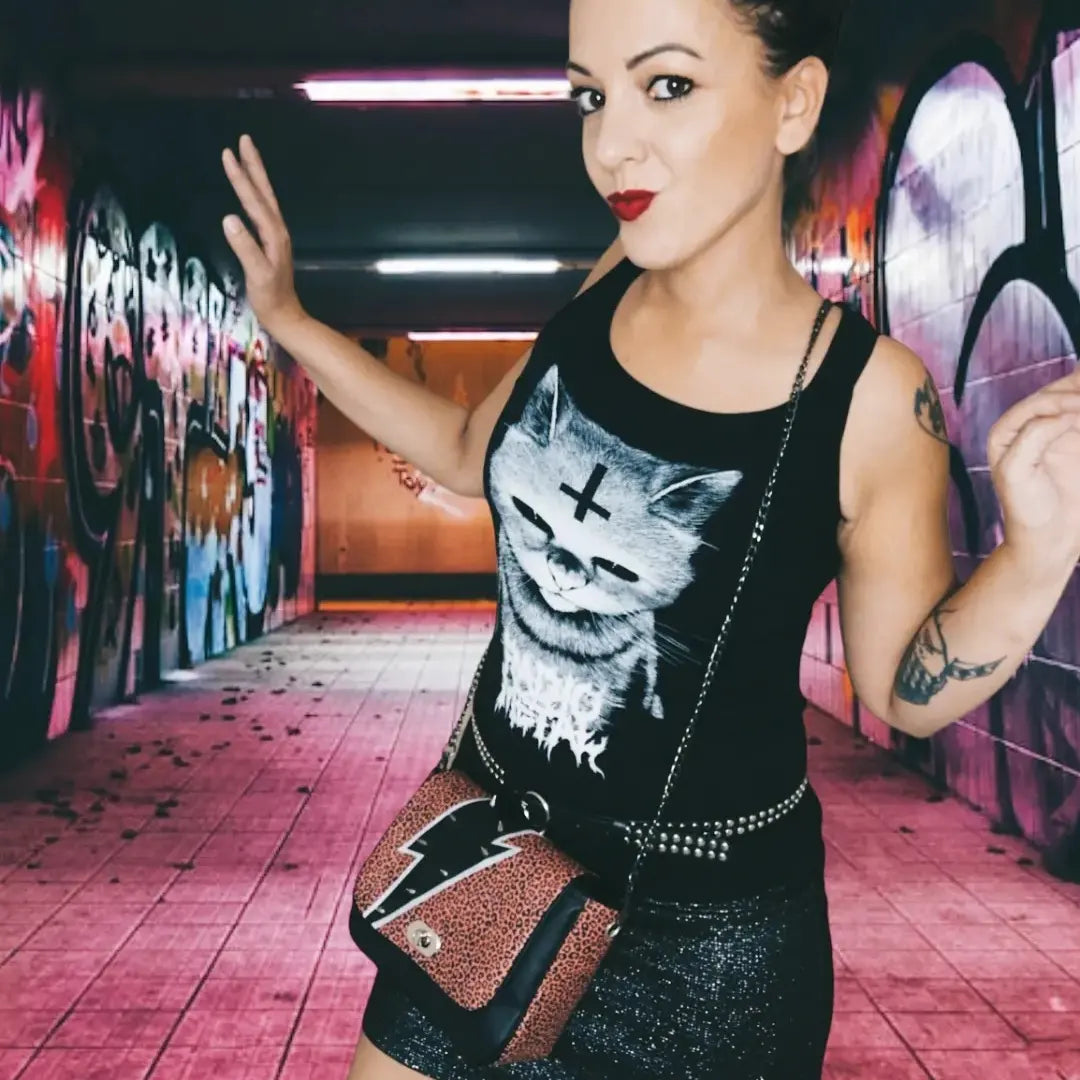 Sac à rabat motif léopard terracotta et noir, décoré d'un éclair en simili cuir noir, argent et de spikes en métal argent. Muni d'un fermoir tourniquet argent et d'une chaîne argent bandouilère amovible.