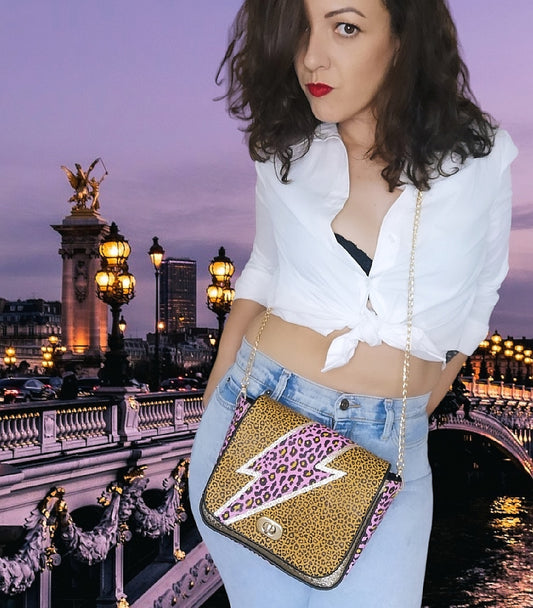 Sac à main à rabat Les RoQuettes, motif léopard camel avec un éclair fuchsia et doré style David Bowie, muni d'une chaîne bandoulière dorée et d'un fermoir tourniquet.