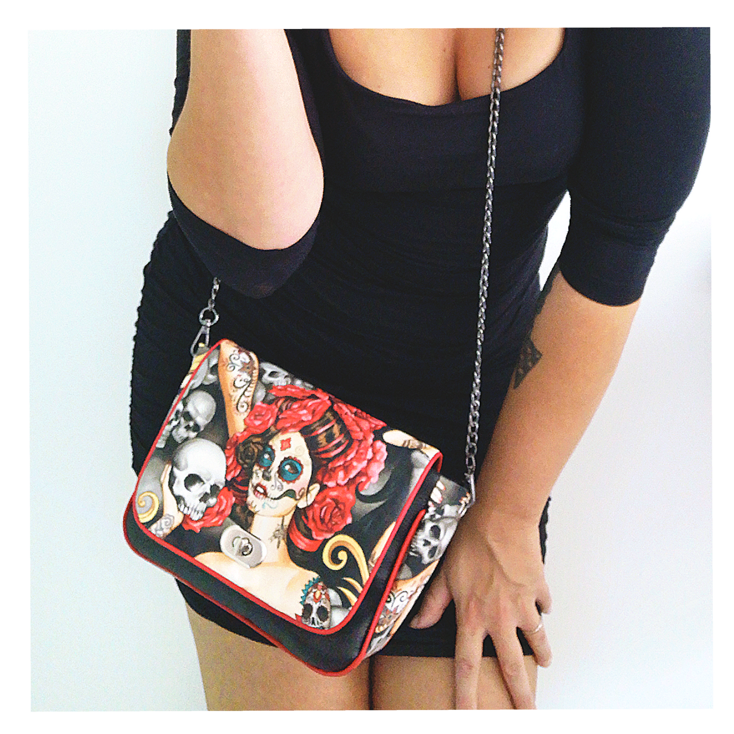 Sac à main à rabat motif têtes de mort mexicaine, calavera et fleurs. Munit d'un fermoir tourniquet argent et d'une chaîne argent bandouilère amovible.