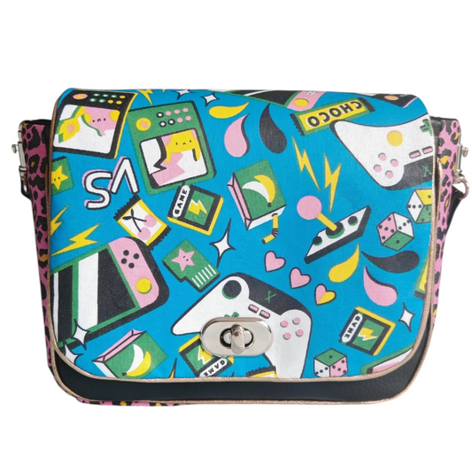 Sac à main bandoulière Les RoQuettes

Modèle Lady geek pour un style très coloré inspiré des années 80, geek style. 

Sac à rabat motif jeux vidéos des année 80 multicolore et de  léopard rose.

Muni d'un fermoir tourniquet argent et anse en simili cuir noir amovible.

Petite poche intérieure pour y glisser ses clés.

Dimensions: 16 x 24 x 7 cm

Longueur de la anse: 110 cm

Matière: coton/viscose et simili cuir / doublure: coton