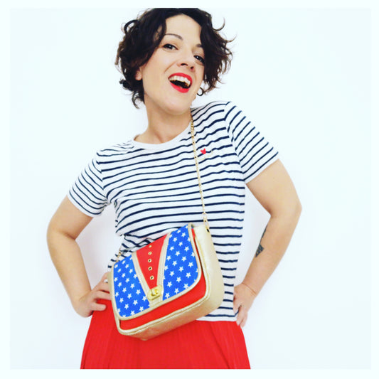 Sac à rabat motif bleu étoiles blanches, doré et rouge et décoré d'œillets en métal doré.   Muni d'un fermoir tourniquet doré et d'une chaîne doré bandoulière amovible.